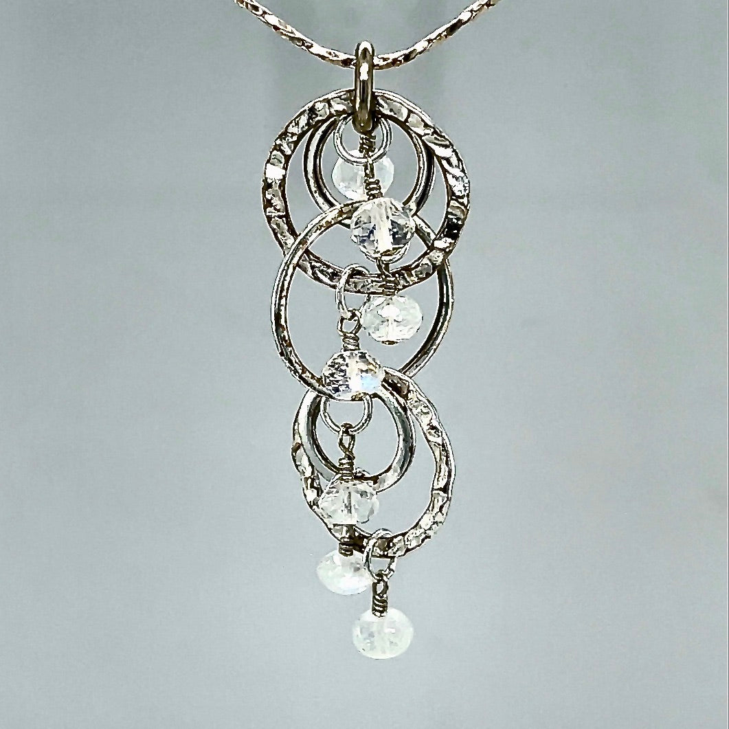 Closeup of beachlove rainbow moonstone & silver circles pendant on gray background