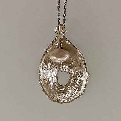 Closeup pink keshi pendant with bright scratch-brushed teardrop disc and shell bail / Arpaia
